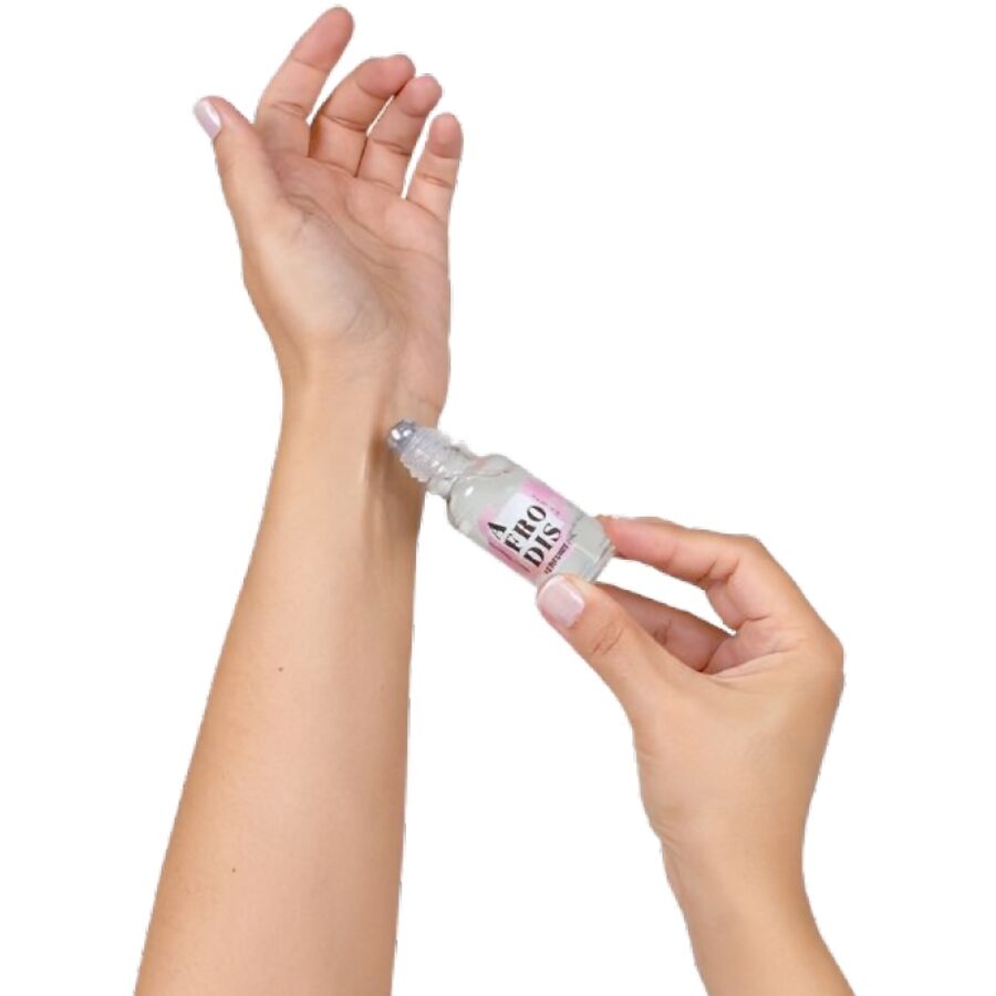 Application de l'huile aux pheromones Afrodis sur le poignet, flacon roll-on tenu en main. Geste simple pour deposer la fragrance caramel et soigner son sillage seducteur.