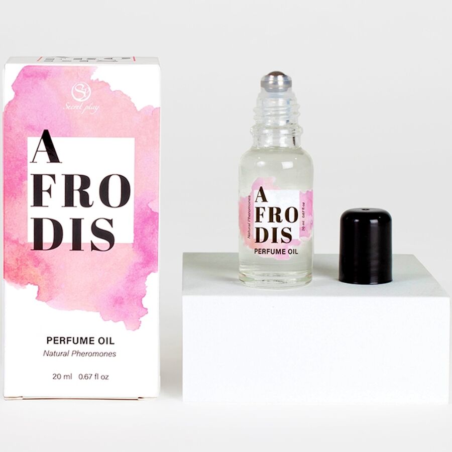 Flacon roll-on d'huile aux pheromones Afrodis bouchon retire, pose sur un socle blanc pres de sa boite rose. Format 20 ml nomade, deux applications pour une fragrance caramel.