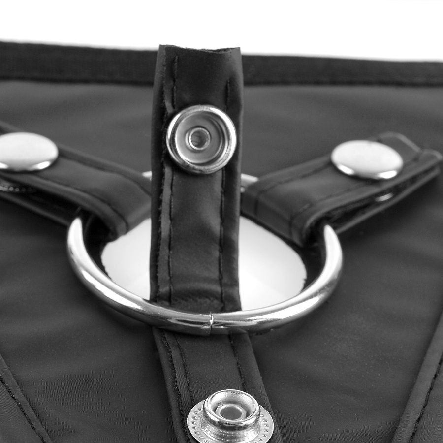 Très gros plan sur l'anneau métallique central et les boutons-pression du harnais Perfect Fit, montrant la finition surpiquée de la plaque en textile noir.