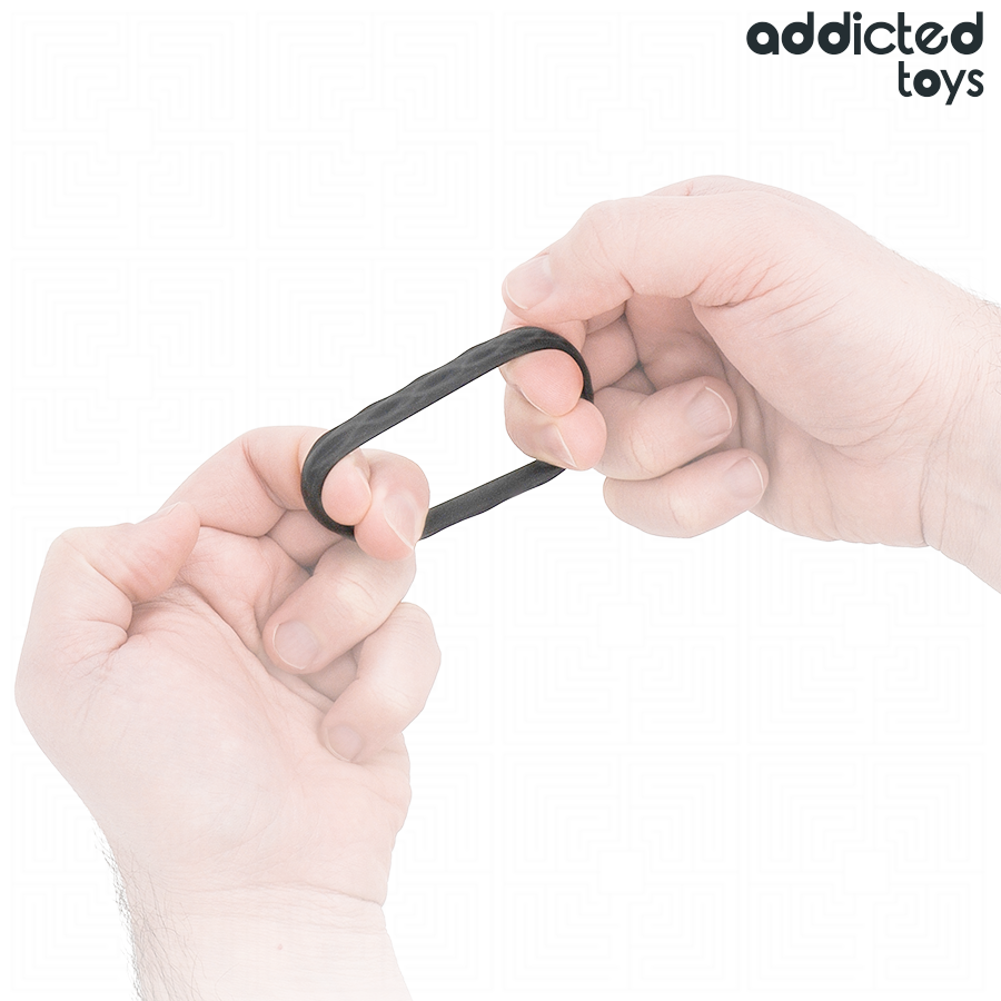 Anneau penien texture Addicted en silicone souple etire entre deux doigts pour illustrer son elasticite, surface nervuree pensee pour un maintien ferme et confortable.