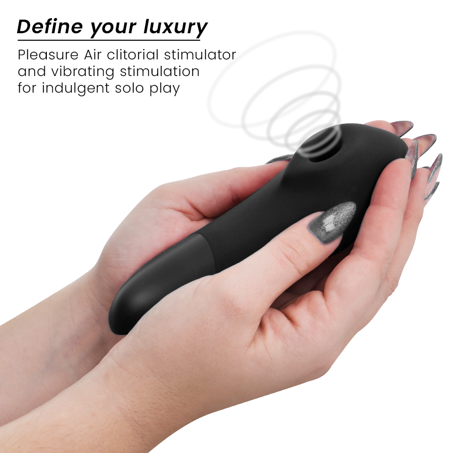 Stimulateur clitoridien noir Womanizer Enhance tenu entre deux mains aux ongles gris : embout d'air pulsé visible, corps ergonomique lisse en silicone, sans anatomie.