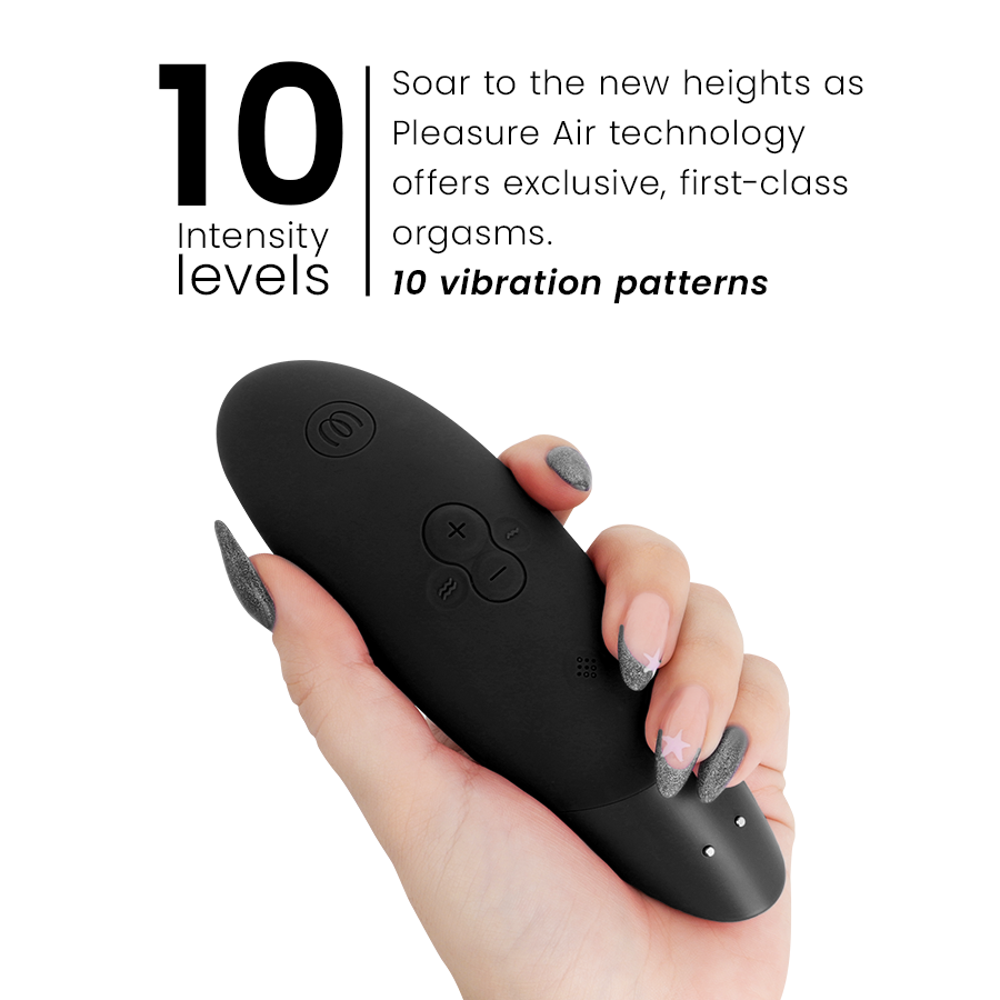 Main tenant le stimulateur clitoridien noir Womanizer Enhance de profil près du visuel '10 intensity levels' : embout d'aspiration et boutons +/- en silicone mat.