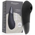 Boîte Womanizer 'Enhance' gris-beige à gauche et stimulateur clitoridien noir à droite : embout de succion rond et corps galbé bicolore en silicone, sans anatomie.