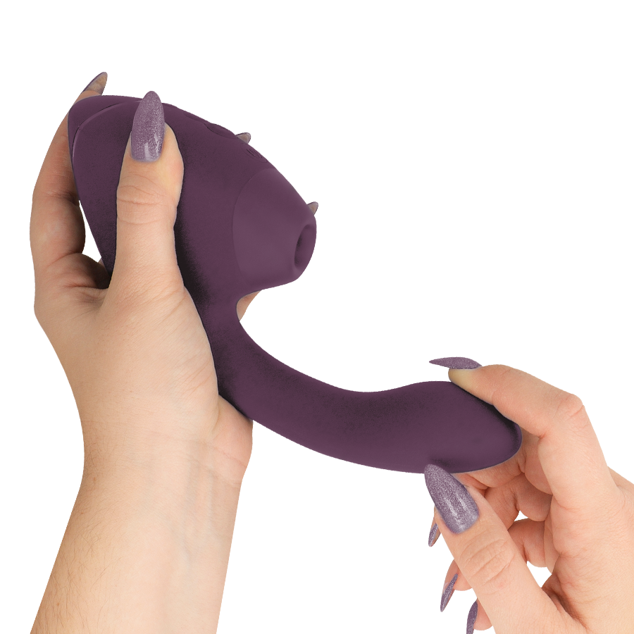 Main tenant le stimulateur double prune Womanizer, gros plan sur l'embout de succion clitoridien arrondi et le bras vibrant interne lisse, sans relief anatomique.