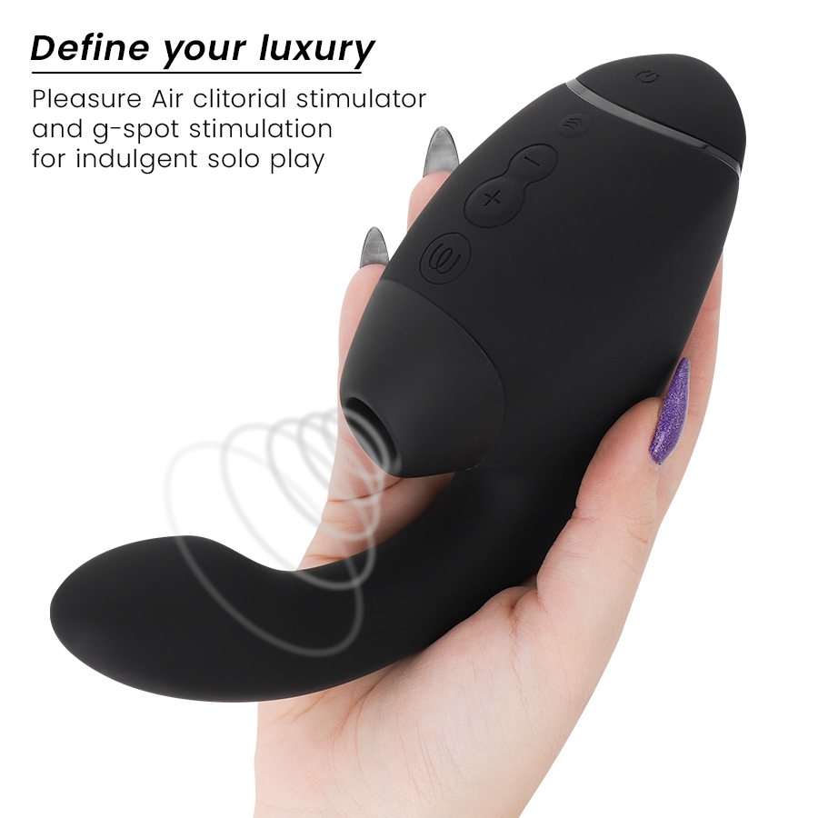Main aux ongles violets tenant le stimulateur double noir Womanizer de face : embout d'air pulsé pour le clitoris et tige interne vibrante courbée en silicone.