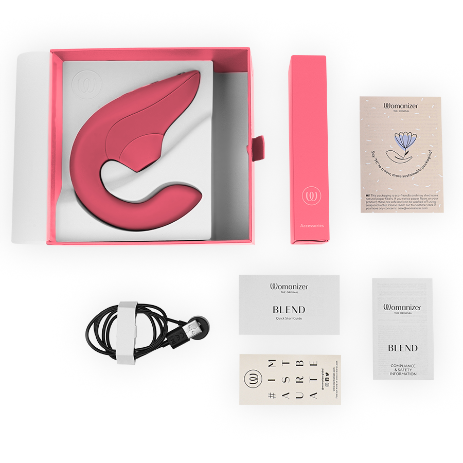 Vibromasseur lapin Womanizer rose présenté avec son écrin corail, câble de charge magnétique, notices et cartes d'accessoires disposés sur fond clair.