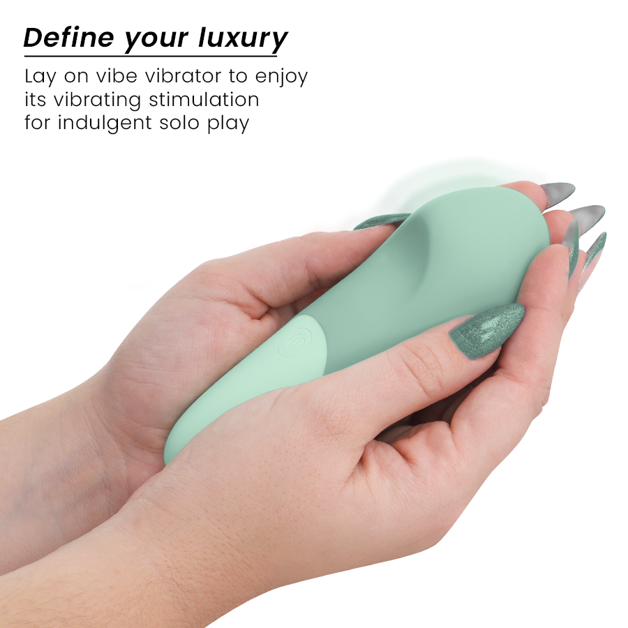 Main aux ongles vernis tenant le vibromasseur à poser UltraWave Vibe vert sauge, forme galbée lisse, texte Define your luxury vantant la stimulation vibrante en solo.