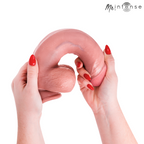 Gode realiste Intense en silicone chair plie en boucle par deux mains aux ongles rouges, illustrant la flexibilite extreme de la matiere veinee.