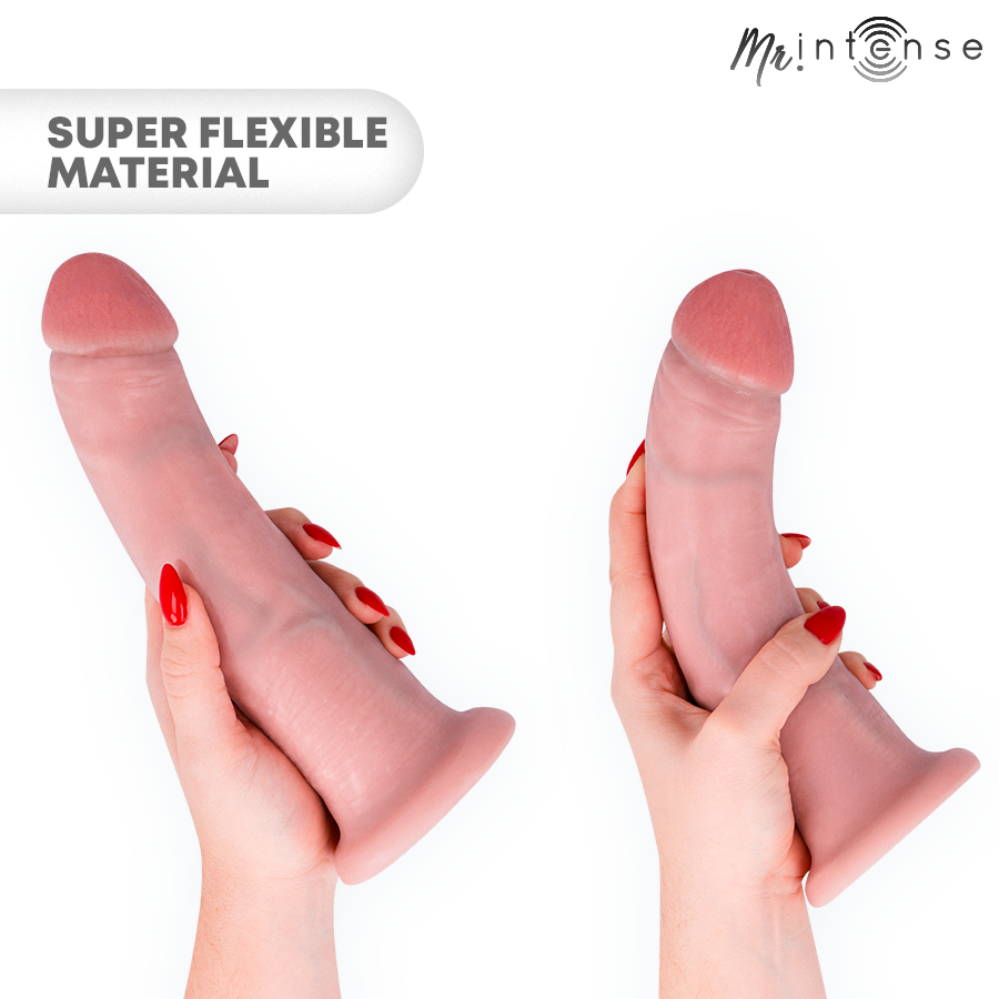 Gode realiste Intense plie par une main aux ongles rouges sous deux angles, demontrant la souplesse du materiau et la texture peau avec gland marque