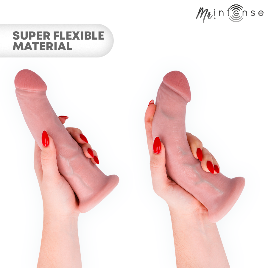 Gode realiste Intense plie entre les doigts d'une main aux ongles rouges, demontrant la souplesse du materiau et la texture peau avec gland marque