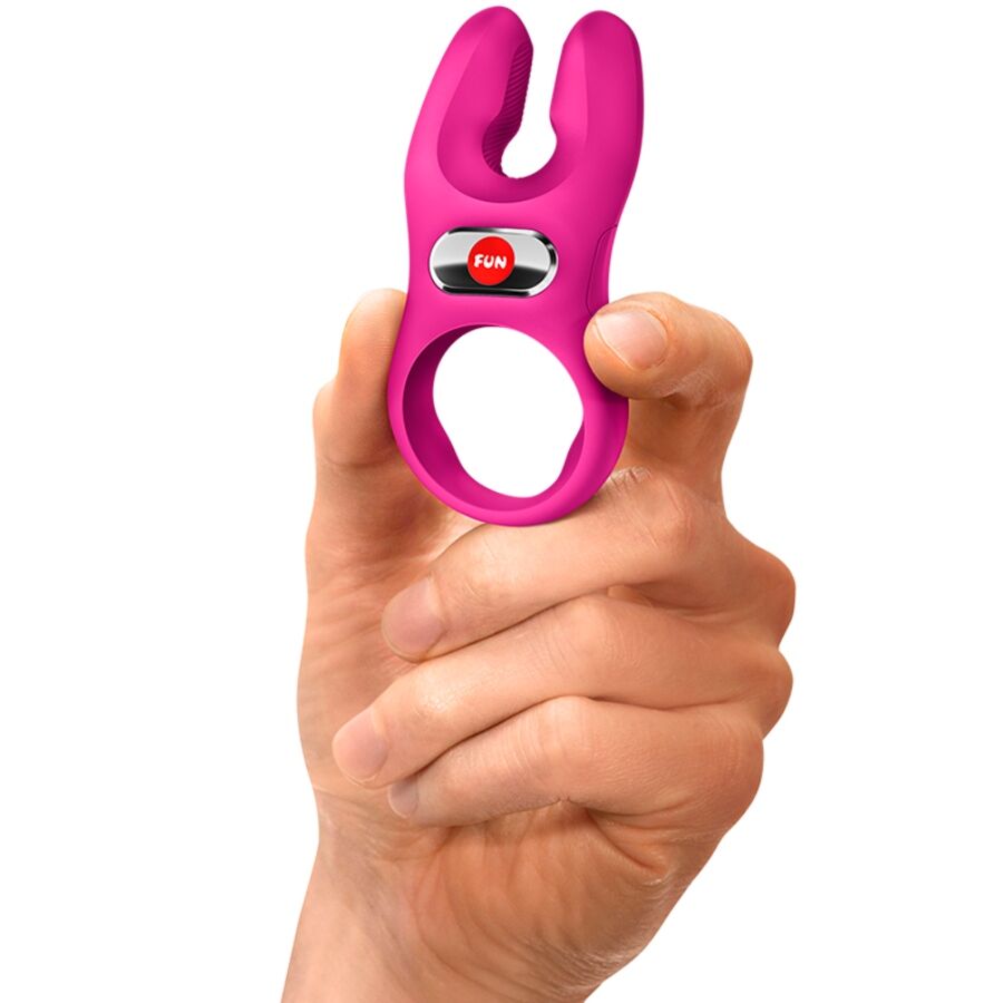 Cockring vibrant NOS Pro en silicone rose tenu en main, qui montre son format compact, son bouton de commande FUN et son anneau souple a deux moteurs pour la stimulation a deux.