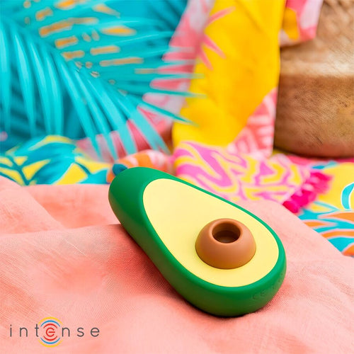 Stimulateur clitoridien avocat Intense posé sur un décor tropical coloré, format compact en silicone pour une stimulation du clitoris par aspiration discrete.