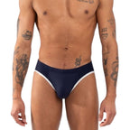 Slip bleu marine vu de face, plan plus large incluant le buste et les avant-bras tatoués.