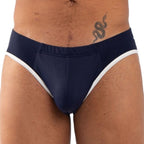 Slip bleu marine vu de face en gros plan sur l'entrejambe, liserés blancs sur les côtés, tatouage de serpent sur la hanche du modèle.