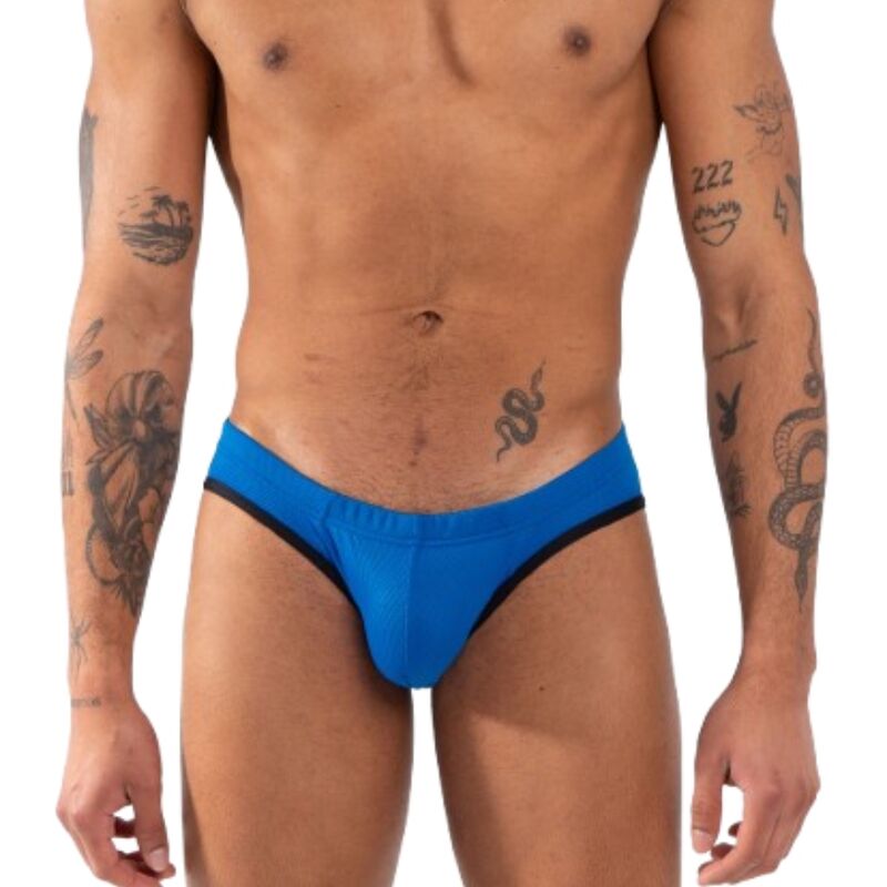 Slip bleu vif vu de face, plan plus large incluant le buste et les avant-bras tatoués.