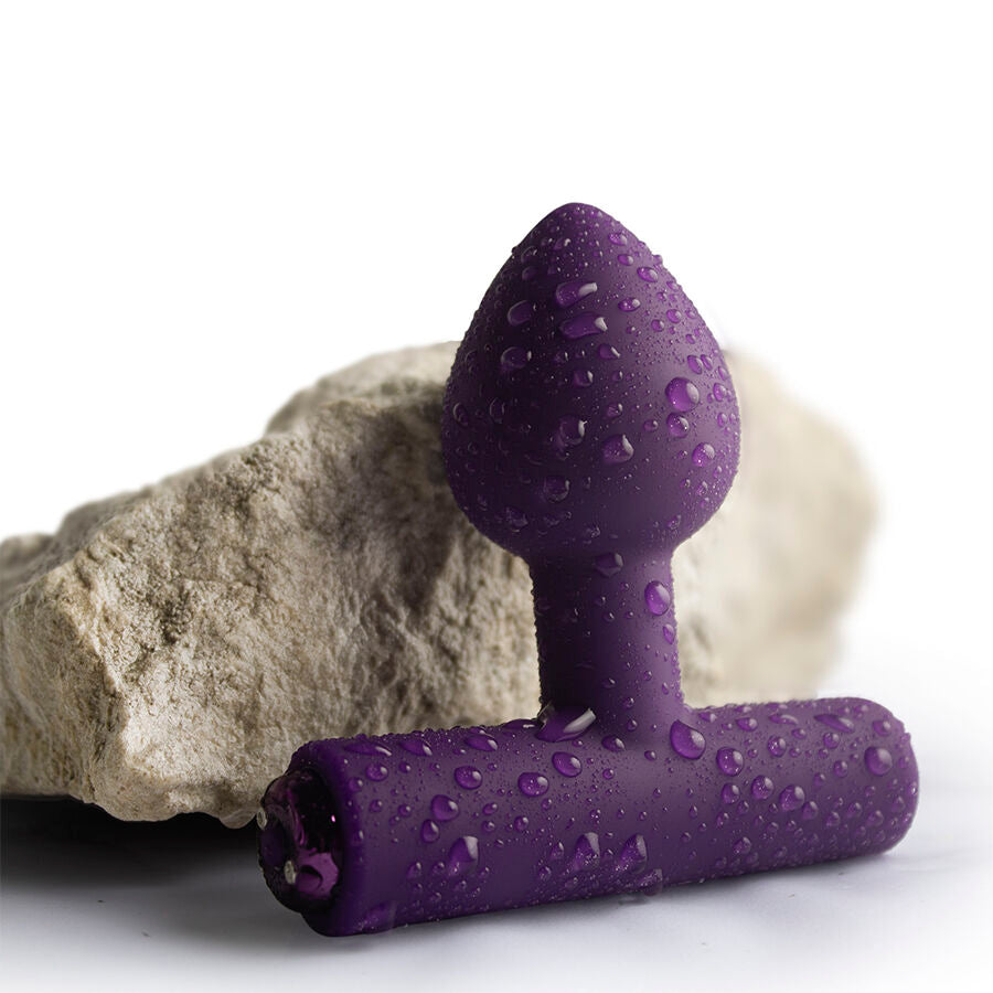 Plug vibrant Nova Astryx violet aubergine, gros plan mouillé posé contre une pierre