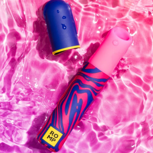 Mini stimulateur Lipstick ROMP en forme de rouge a levres pose dans l'eau sur fond rose, illustrant son design discret et son etancheite a air pulse.