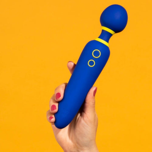 Wand vibrant ROMP tenu en main sur fond orange vif : manche en silicone bleu nuit, tete spherique souple et detail jaune, baguette puissante a 10 modes pour une stimulation externe.