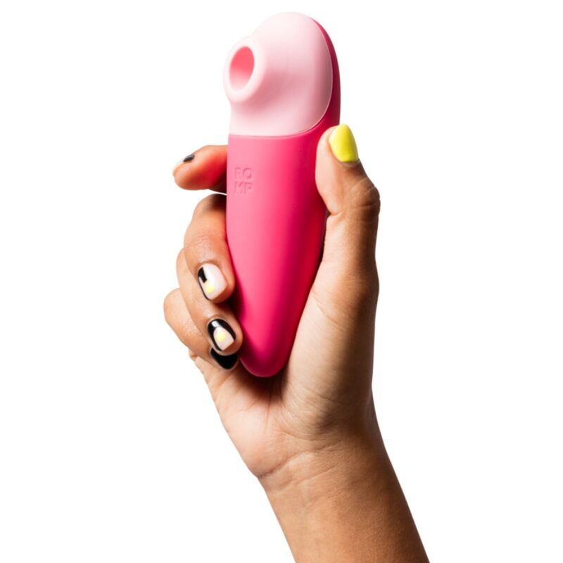 Stimulateur ROMP Shine X rose tenu dans une main, format ergonomique rechargeable avec 10 niveaux d’ondes de pression.