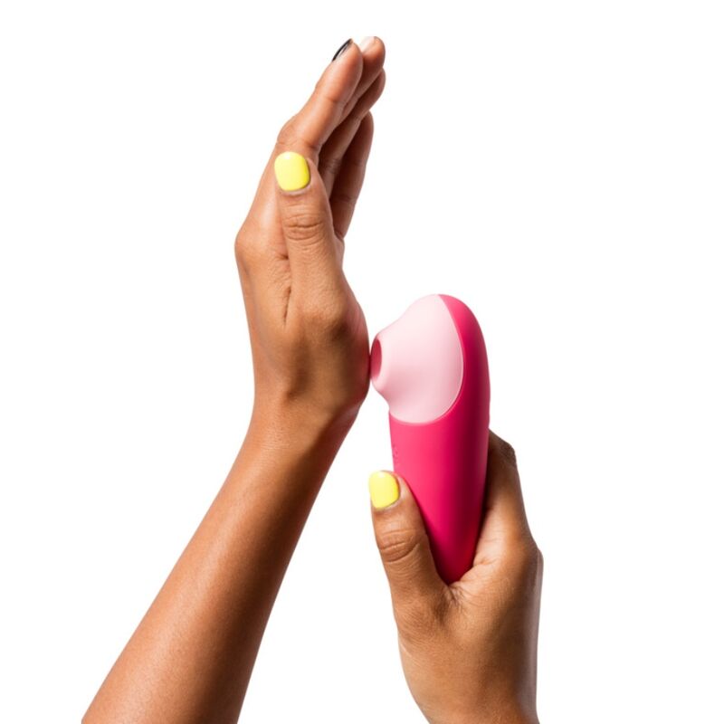 ROMP Shine X rose tenu entre les mains, vue du col flexible et de la tête de stimulation externe par ondes de pression.