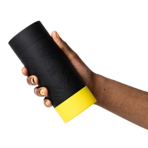 Masturbateur ROMP Dash tenu dans une main par son etui noir texture : format compact type bouteille a base jaune, boitier discret cachant la gaine interne en TPE souple.