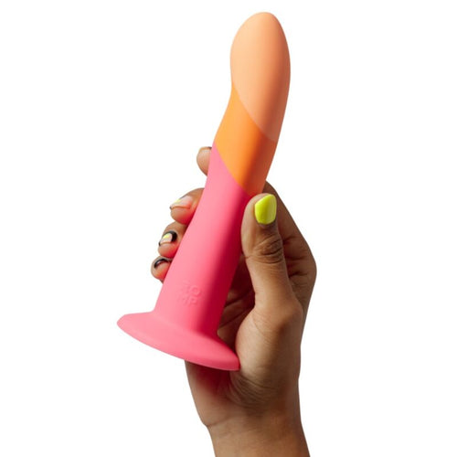 Gode non realiste ROMP Dizz tenu dans une main par sa base ventouse corail : silicone souple au degrade orange et rose, forme incurvee lisse pour une stimulation profonde mains libres.