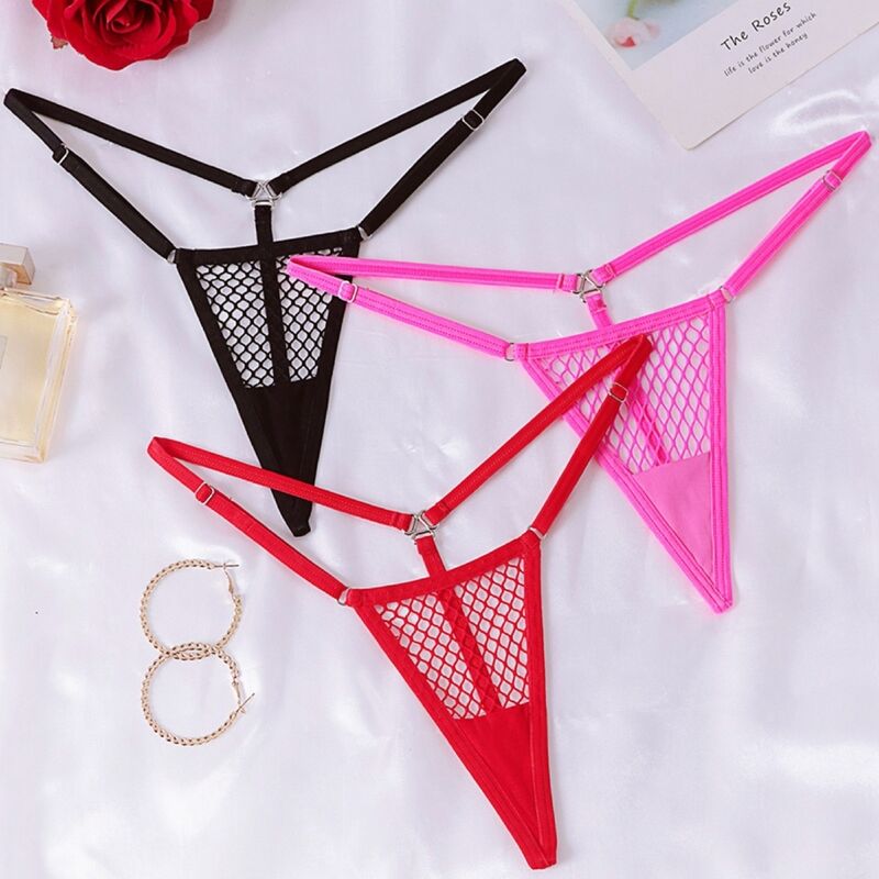 Trois micro-strings resille Chilirose noir, fuchsia et rouge disposes a plat sur satin blanc avec rose et anneaux dores, modele minimaliste a pampilles.
