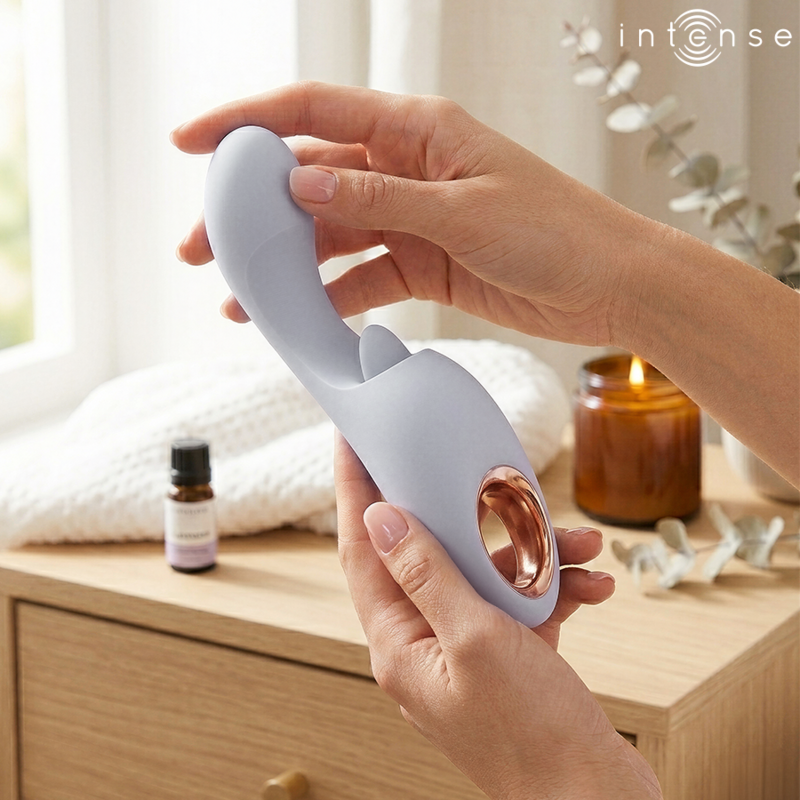 Anya stimulateur multifonctionnel lavande — tenu à deux mains dans une mise en scène cosy avec bougie, huile essentielle et serviette