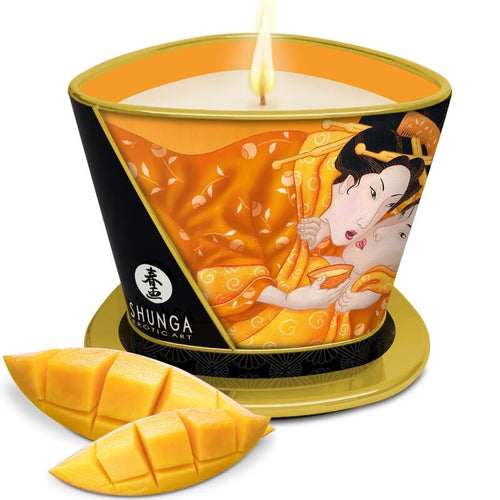Bougie de massage Shunga mangue allumée, avec des tranches de mangue fraîche disposées devant