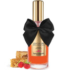 Huile de massage chauffante Light My Fire Bijoux Indiscrets mise en scene avec rayon de miel et framboise, flacon orange a noeud satin, arome fraise des bois gourmand.