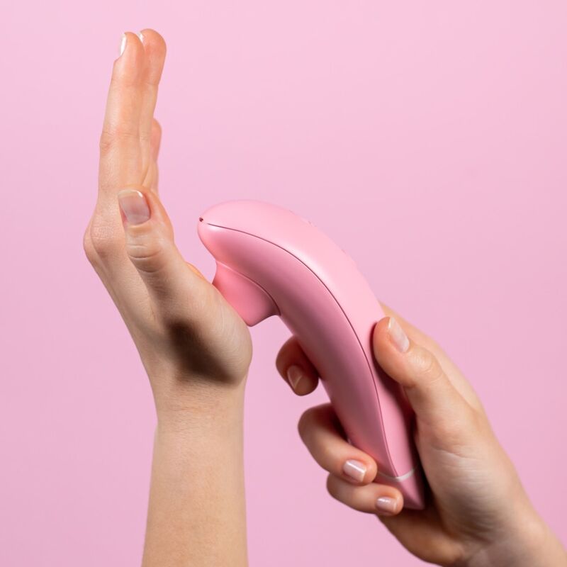 Womanizer Premium Eco rose tenu en main, embout posé contre la paume pour illustrer la stimulation.