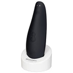 Womanizer Classic 2 Noir présenté sur un support blanc, commandes et contacts de recharge visibles.