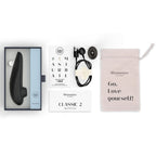 Coffret du Womanizer Classic 2 Noir avec câble de recharge, embout supplémentaire, pochette et guide.