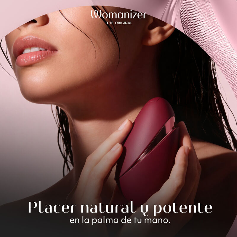Femme tenant le Womanizer Next Liberty Bordeaux avec son capuchon, près de son cou.