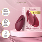 Womanizer Next Liberty Bordeaux ouvert et fermé devant son coffret, avec les indications de recharge USB-C.