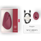 Coffret ouvert du Womanizer Next Liberty Bordeaux, câble USB-C, embout supplémentaire et guide de démarrage.