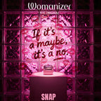 Étui rose du Womanizer Snap ouvert avec le stimulateur Baie écrasée à l’intérieur, devant des blocs de verre.