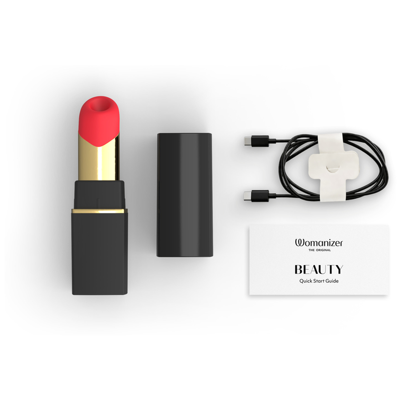 Womanizer Beauty noir et or avec capuchon, câble de recharge et guide de démarrage.