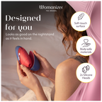Womanizer Next Liberty Rouge et Bleu tenu sur un lit, avec un visuel de la surface douce et des deux embouts.