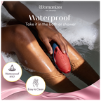 Womanizer Next Liberty Rouge et Bleu tenu au-dessus d’un bain moussant, avec une indication d’étanchéité IPX7.