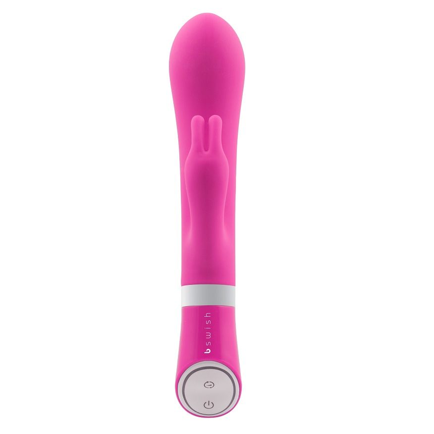 Vibromasseur rabbit Bwild Deluxe rose vif de face, oreilles courtes et tête arrondie, bouton à la base. Corps en silicone lisse, coloris fuchsia uniforme, double stimulation.