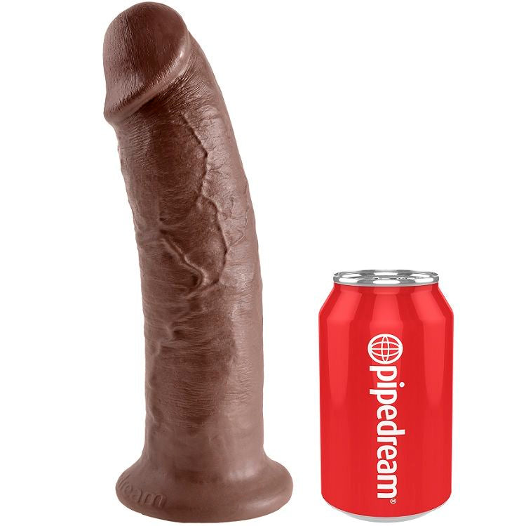 Gode realiste teinte chocolat dresse a cote d une canette Pipedream pour l echelle, gland marque et tige veinee, base ventouse compatible harnais.