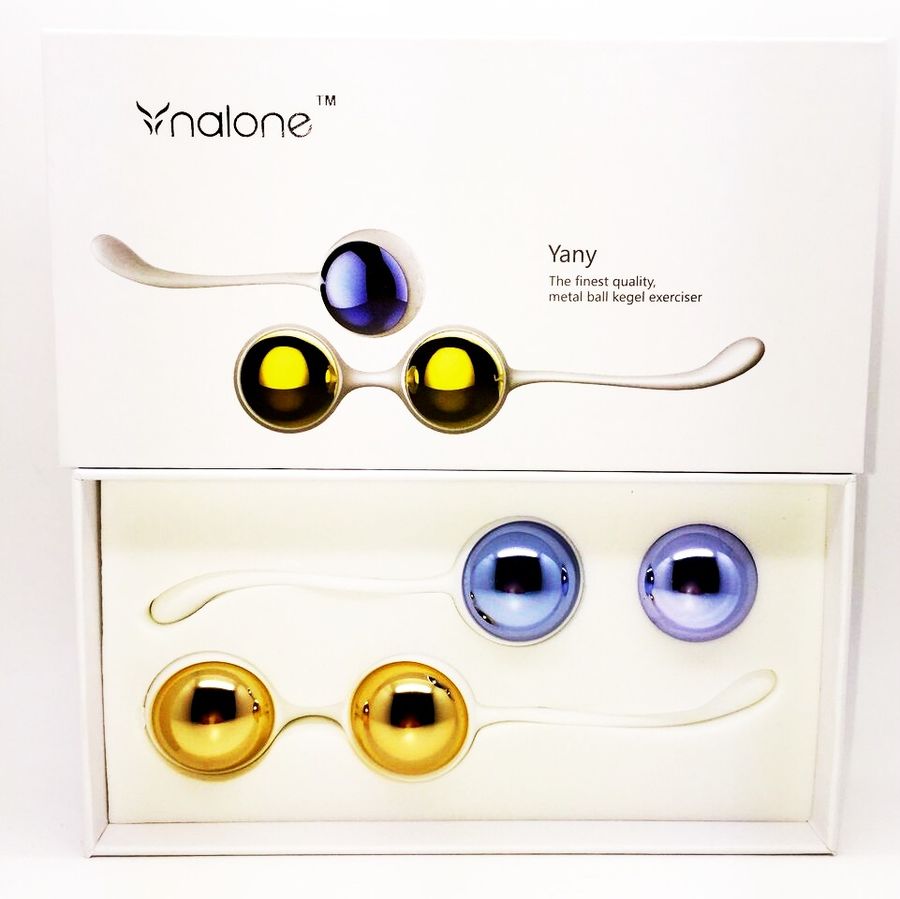 Boîte des boules de Geisha Nalone Yany ouverte montrant les billes métalliques dorées et bleues sur cordons blancs. Exerciseur de Kegel premium, packaging épuré sans visuel cru.