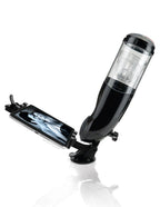 Masturbateur PDX Mega Bator noir fixé par ventouse sur une surface plane, support à pince tenant un téléphone avec image à l'écran, vue en angle avec reflet au sol.