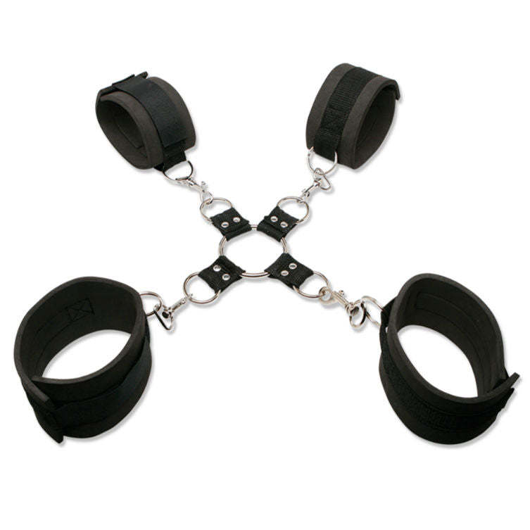 Kit hogtie etale a plat sur fond blanc : quatre manchettes en neoprene noir doublees, attache metallique centrale en croix et mousquetons reliant poignets et chevilles.