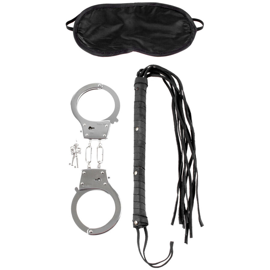 Kit de jeu a deux : masque en satin noir, menottes en acier avec cles et fouet en cuir a fines lanieres, presentes a plat sur fond blanc.