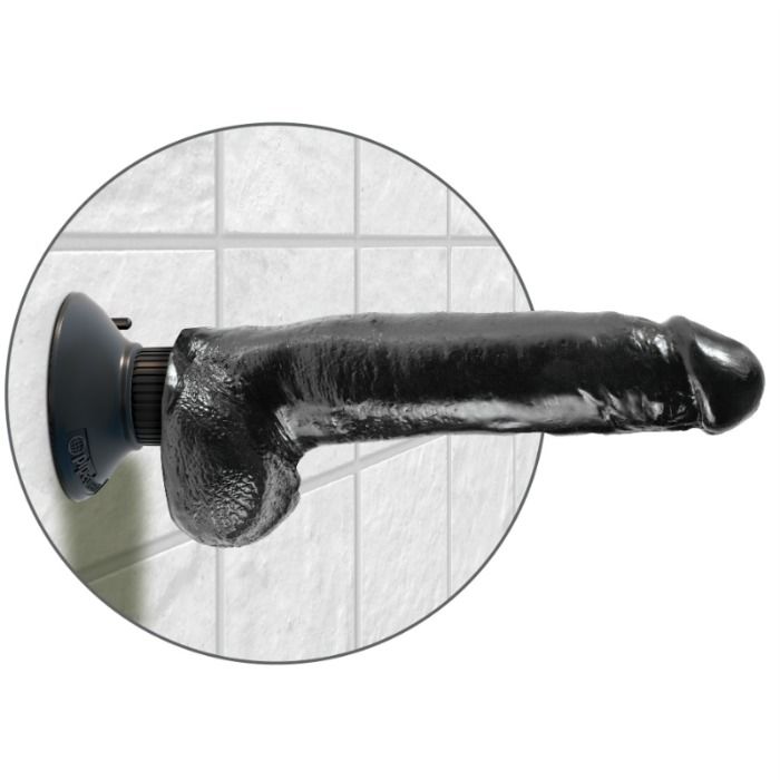 Grand gode a testicules King Cock noir fixe par ventouse sur un mur carrele, tige realiste veinee et bourses a l'horizontale pour un usage mains libres sous la douche.