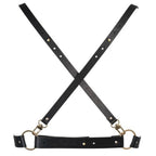 Harnais de corps femme vegan Bijoux Indiscrets en sangles noires croisees a anneau et mousquetons dores, presente a plat, accessoire BDSM modulable a porter sur la peau.