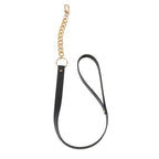 Laisse amovible noire Bijoux Indiscrets a chaine doree et boucle de cuir vegan, presentee a plat, complement du collier BDSM reglable pour jeux de domination douce.