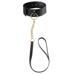 Collier BDSM noir Bijoux Indiscrets avec laisse amovible en polyurethane vegan, presente a plat avec chaine doree, accessoire reglable a double usage mode et bondage.
